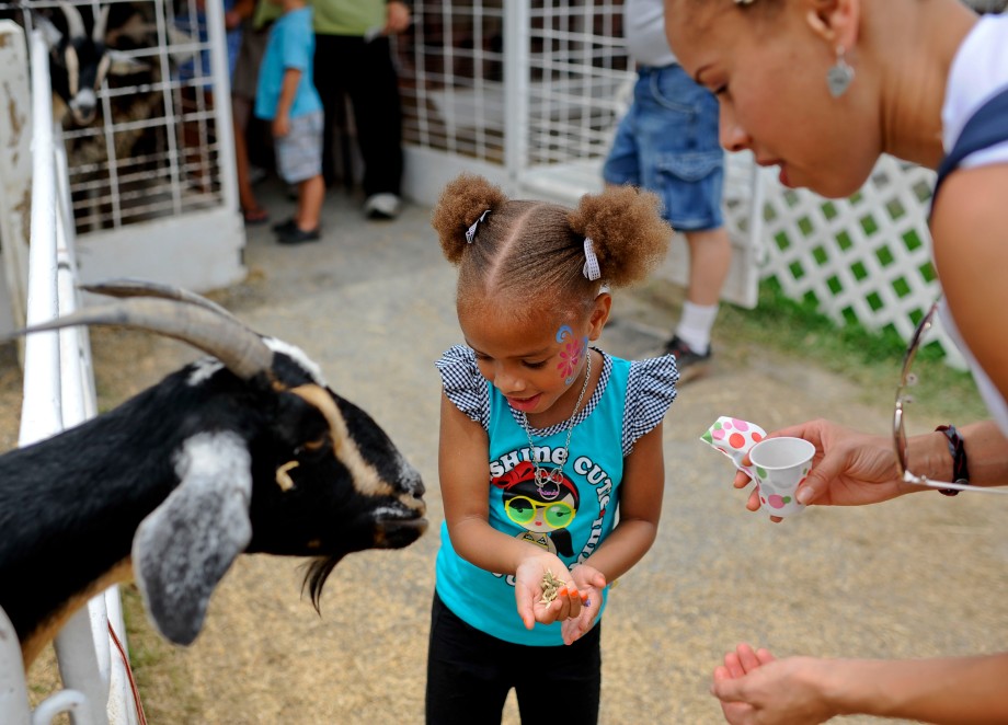 SAM OWENS | The Roanoke Times;  Demi Hatch, 4, (center) feeds a goat at the Hedrick's Petting Zoo booth at the Salem Fair while enjoying the fair with her mother, Deja Hatch (right), Sunday afternoon, July 7, 2013.